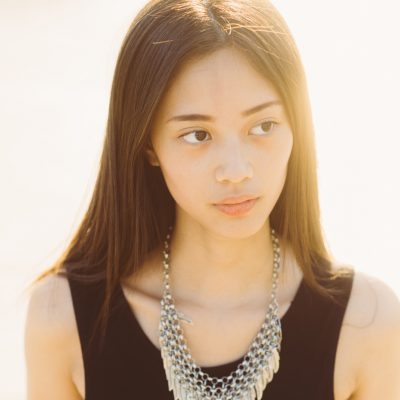 young woman outdoor posing looking away back light - influencer, blogger concept